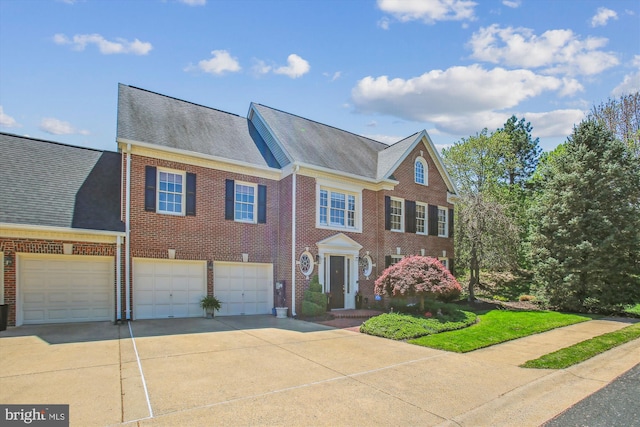 colonial inspired home with brick siding, driveway, and roof with shingles