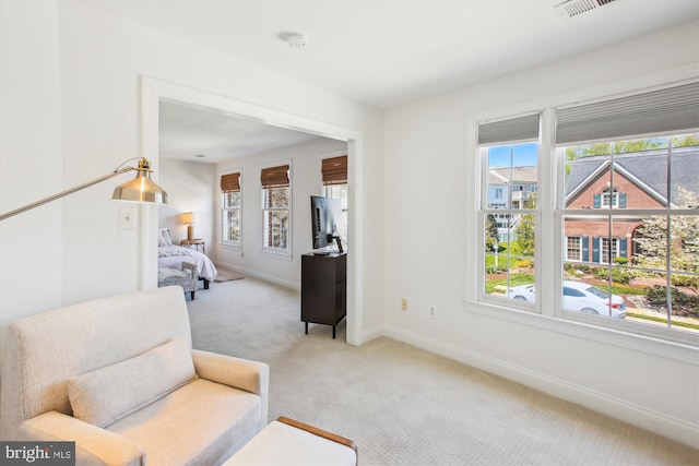 living area featuring visible vents, baseboards, carpet, and a healthy amount of sunlight