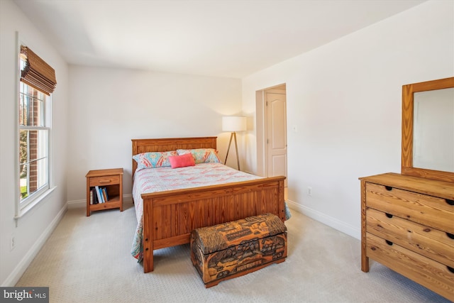 bedroom with multiple windows, light colored carpet, and baseboards