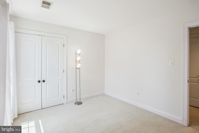 unfurnished bedroom with a closet, visible vents, carpet, and baseboards