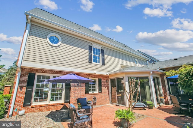 rear view of property featuring brick siding and a patio area