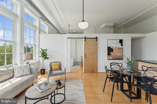 living area featuring a barn door, light wood finished floors, and baseboards
