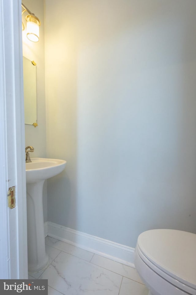 bathroom featuring a sink, baseboards, toilet, and marble finish floor