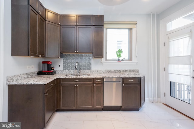 kitchen with plenty of natural light, dark brown cabinetry, stainless steel dishwasher, a sink, and marble finish floor