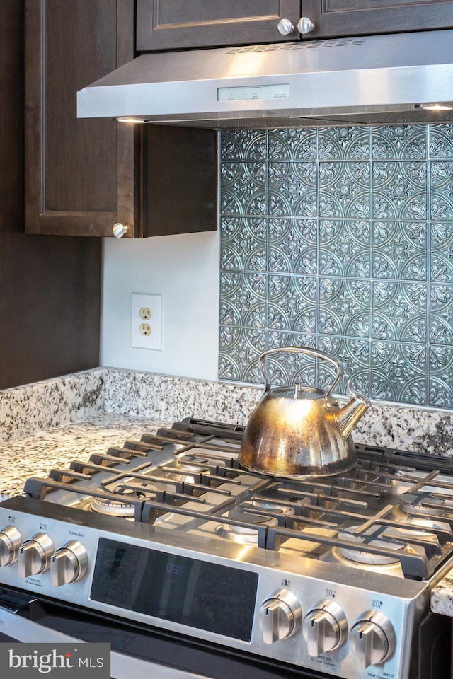 details featuring gas range, dark brown cabinetry, extractor fan, and light stone countertops