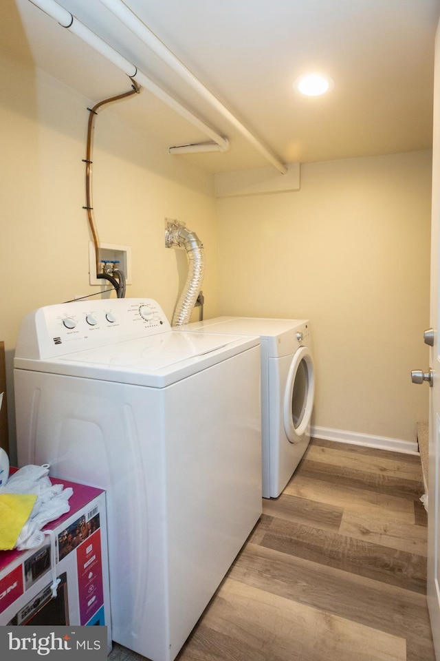 laundry area with baseboards, laundry area, light wood finished floors, and washer and clothes dryer