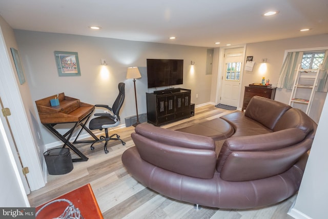 living room featuring baseboards, recessed lighting, light wood-style flooring, and electric panel