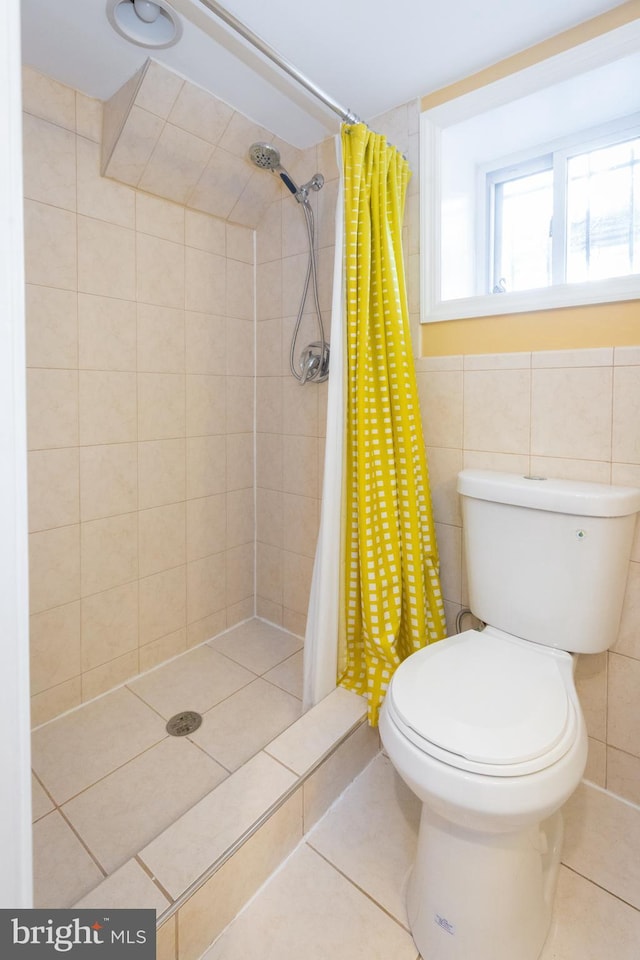 bathroom featuring tile patterned floors, tile walls, toilet, and a shower stall