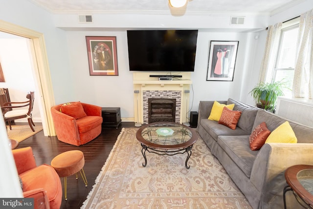 living room featuring visible vents, ornamental molding, wood finished floors, and a tile fireplace