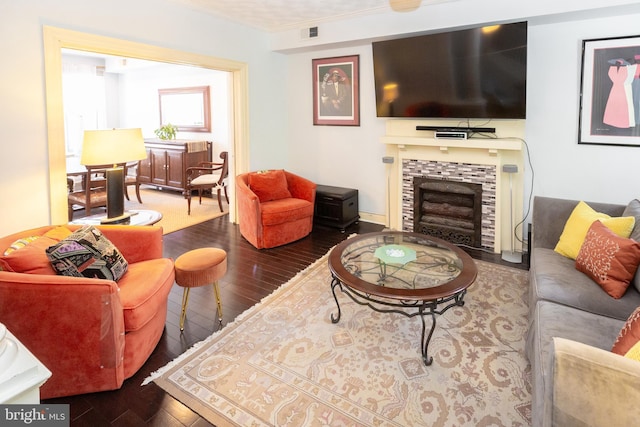 living area featuring visible vents, ornamental molding, a tile fireplace, and hardwood / wood-style floors