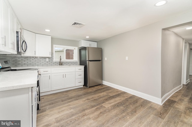 5300 Bino Rd, Greencastle, PA 17225 - kitchen featuring light wood finished floors, backsplash, visible vents, a sink, and appliances with stainless steel finishes