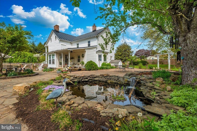 15539 Liberty Rd, Mount Airy, MD 21771 - rear view of property featuring a garden pond, a standing seam roof, a chimney, fence, and a ceiling fan