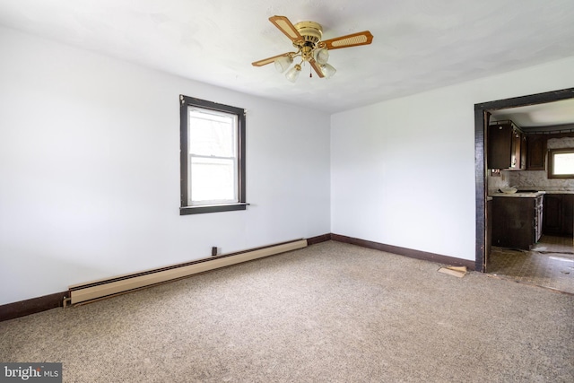 spare room featuring a baseboard heating unit, a ceiling fan, baseboards, and carpet floors