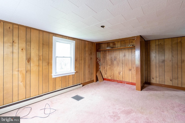 empty room featuring a baseboard radiator, wooden walls, carpet flooring, and baseboards
