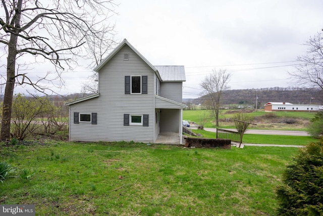back of property featuring a lawn and metal roof