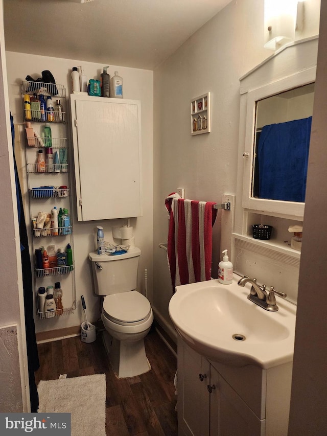 bathroom with wood finished floors, vanity, and toilet