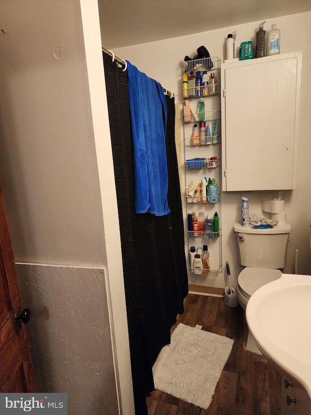 full bath with toilet, wood finished floors, and curtained shower