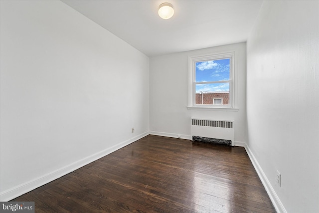 unfurnished room with dark wood finished floors, radiator heating unit, and baseboards