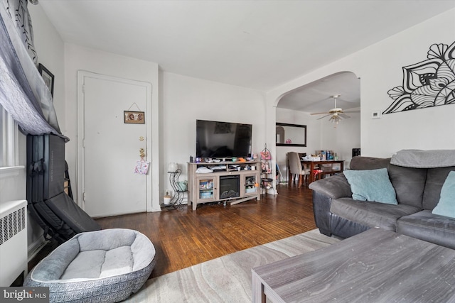 living room with arched walkways, radiator, wood finished floors, and ceiling fan