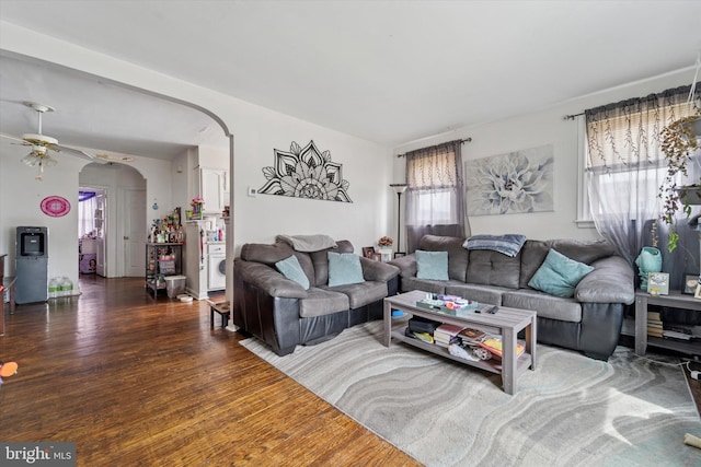 living area featuring ceiling fan, arched walkways, and wood finished floors