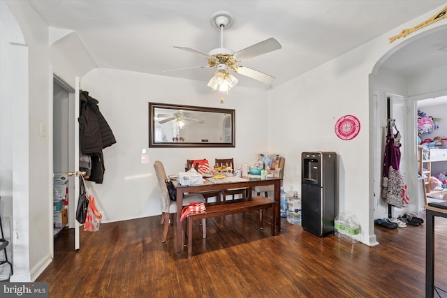 dining space with arched walkways, wood finished floors, and a ceiling fan