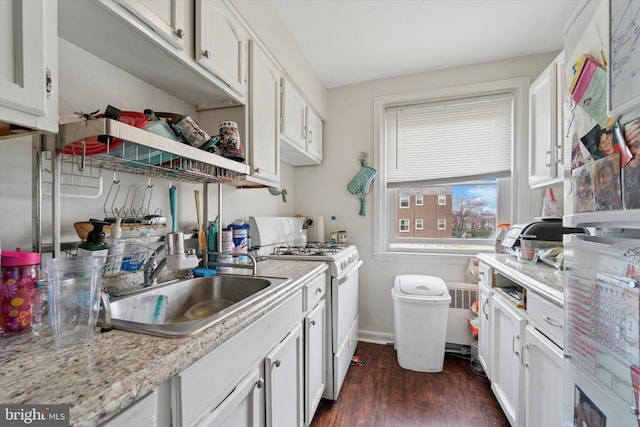 kitchen with white gas range, a sink, light countertops, white cabinetry, and dark wood-type flooring
