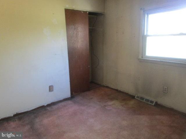 unfurnished bedroom with visible vents, carpet, and a closet