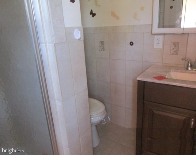 bathroom featuring toilet, vanity, and tile walls