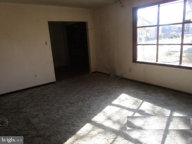 spare room featuring carpet flooring and baseboards