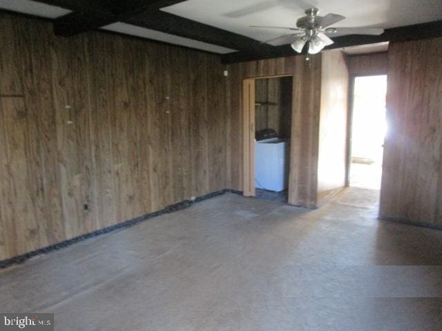 spare room featuring wood walls, beam ceiling, and ceiling fan