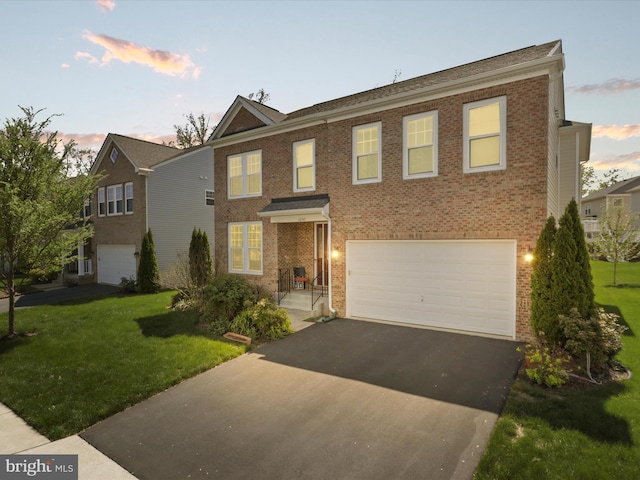 view of front facade with brick siding, aphalt driveway, a lawn, and a garage