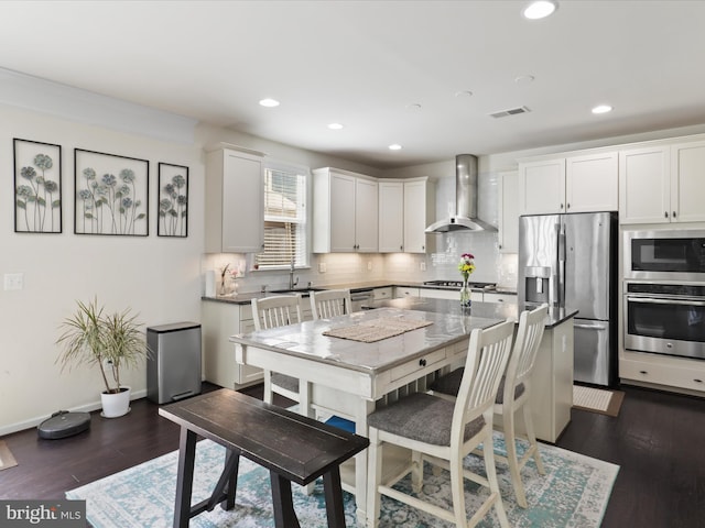 kitchen featuring visible vents, recessed lighting, decorative backsplash, wall chimney range hood, and appliances with stainless steel finishes