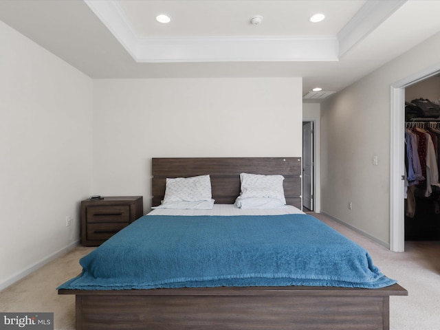 bedroom featuring a spacious closet, crown molding, carpet flooring, and a raised ceiling
