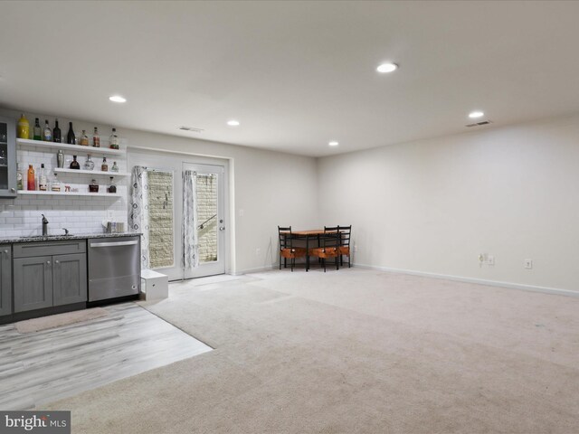 bar featuring a sink, wet bar, visible vents, light colored carpet, and dishwasher
