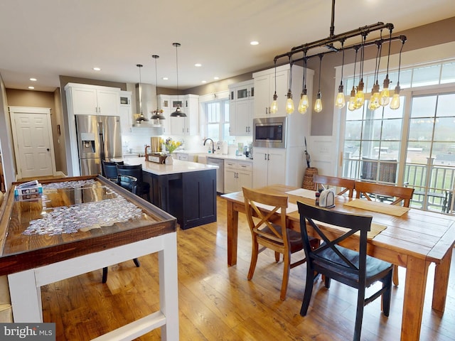 219 Pepper Ridge Dr, Spring Mills, PA 16875 - kitchen with stainless steel appliances, white cabinetry, wall chimney range hood, light countertops, and pendant lighting