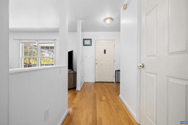corridor with light wood-type flooring and baseboards