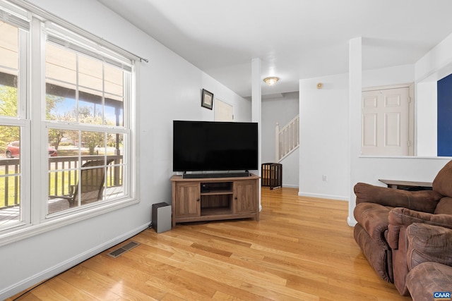 living room with light wood finished floors, visible vents, and a healthy amount of sunlight