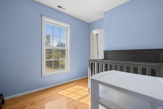 bedroom featuring light wood-style flooring, visible vents, and baseboards