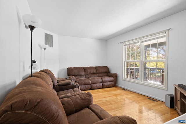 living room featuring light wood-type flooring, baseboards, and visible vents