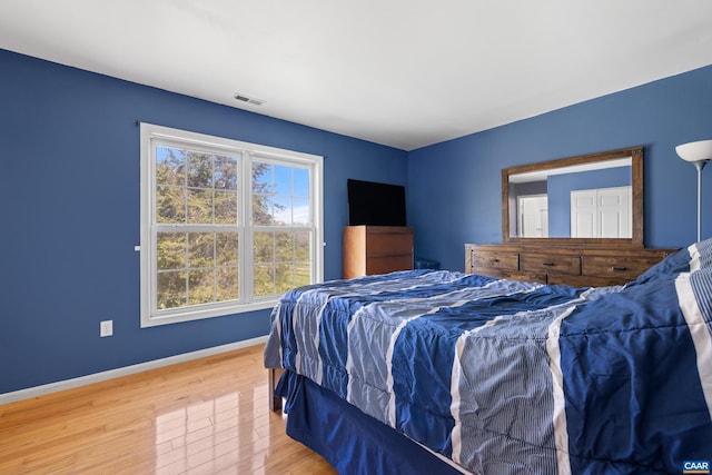 bedroom with baseboards, wood finished floors, and visible vents