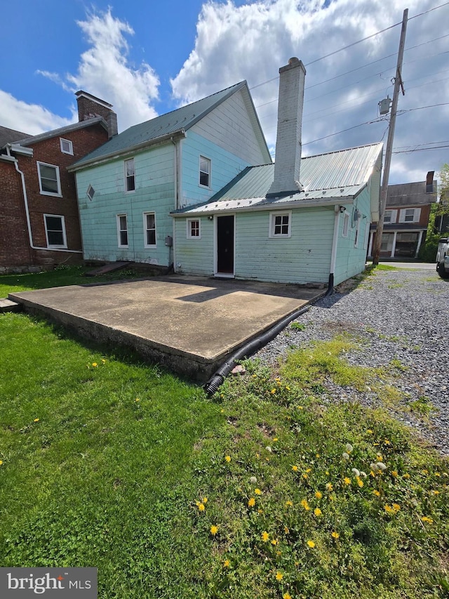 13177 Main St, Fort Loudon, PA 17224 - rear view of house featuring a lawn, a patio, a chimney, and metal roof