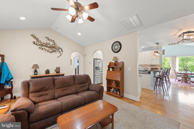 living area with a ceiling fan, recessed lighting, lofted ceiling, light wood finished floors, and arched walkways