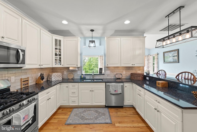 kitchen featuring appliances with stainless steel finishes, a sink, a peninsula, recessed lighting, and white cabinetry