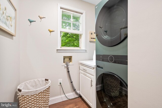 33 Fern Ct, Front Royal, VA 22630 - laundry area featuring stacked washing machine and dryer, wood finished floors, cabinet space, and baseboards
