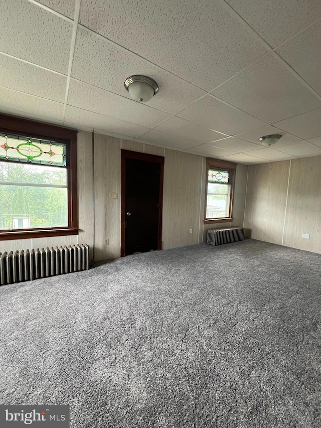 451 Main St, Ashland, PA 17921 - spare room featuring radiator, a paneled ceiling, carpet floors, and wooden walls