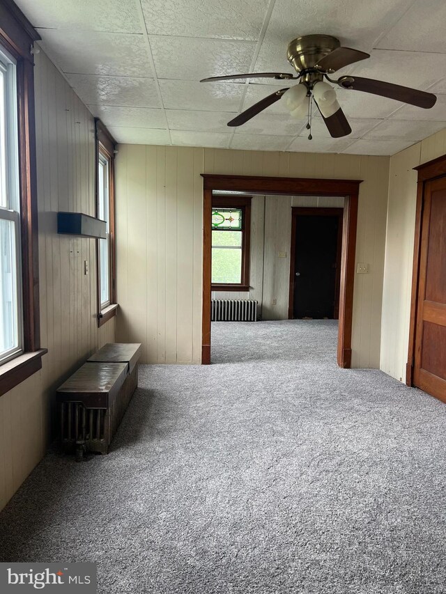 451 Main St, Ashland, PA 17921 - empty room with radiator heating unit, carpet, wooden walls, and ceiling fan