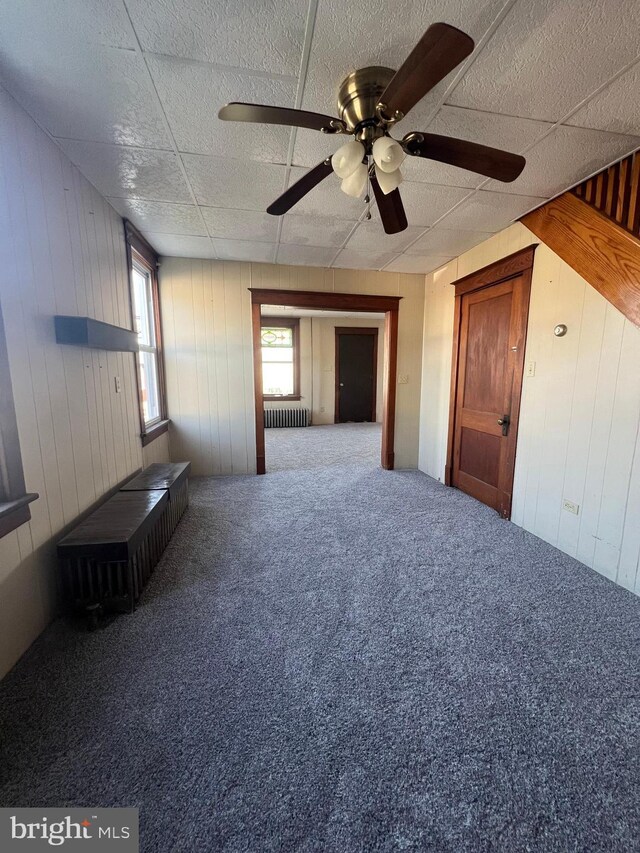 451 Main St, Ashland, PA 17921 - unfurnished room with carpet, a paneled ceiling, wood walls, radiator heating unit, and ceiling fan