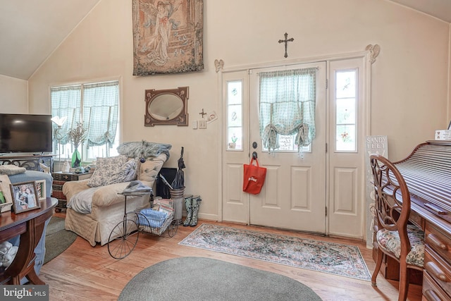 foyer with baseboards, high vaulted ceiling, and wood finished floors