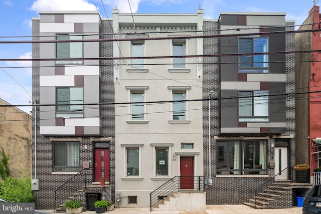 view of front facade featuring brick siding, entry steps, and stucco siding
