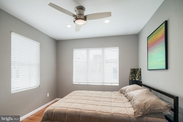 bedroom featuring recessed lighting, baseboards, wood finished floors, and multiple windows